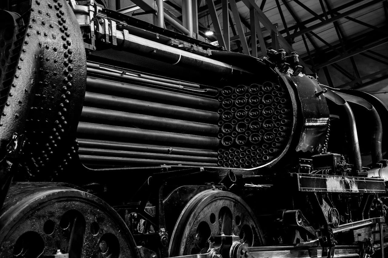 Black and white image of a vintage steam train engine showcasing intricate metallic details.